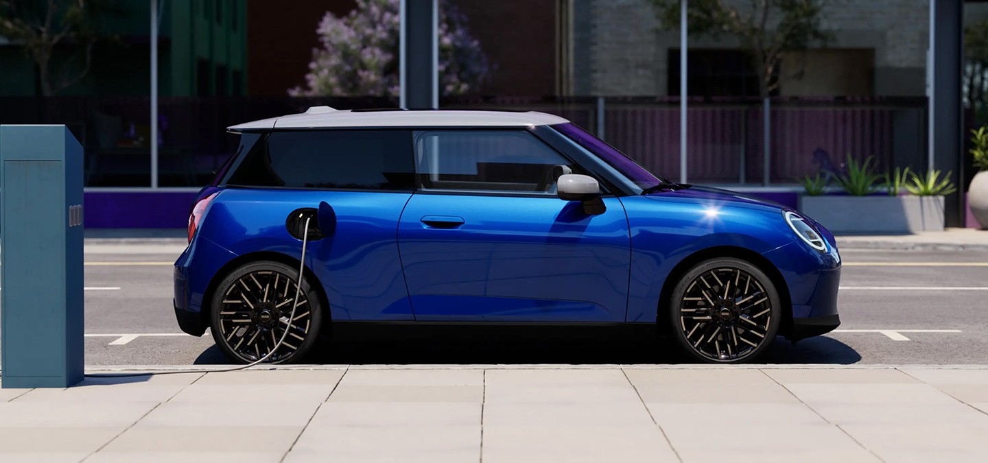 Side View of Blazing Blue all-electric MINI Cooper parked on pavement beside a charging station